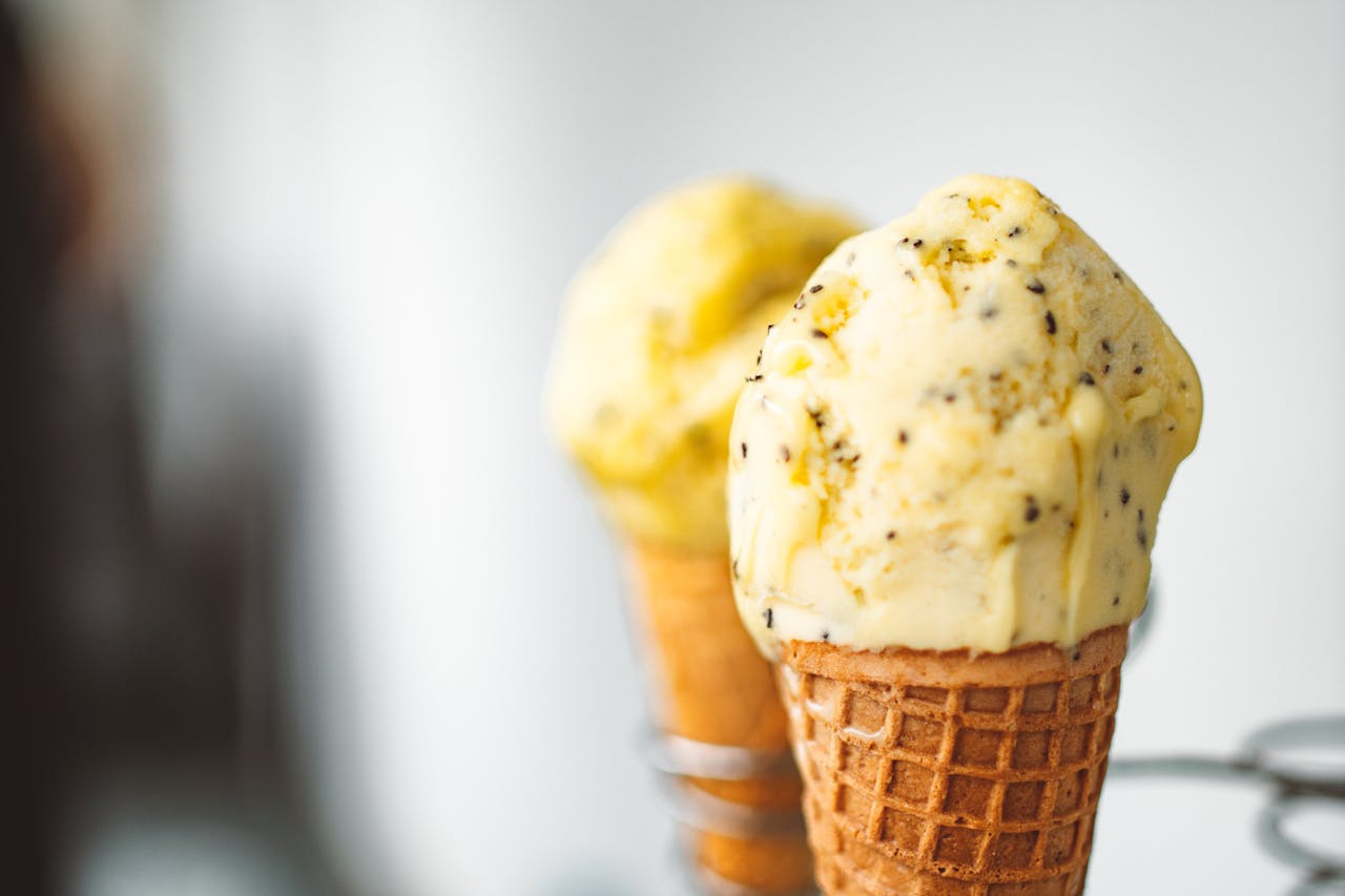 Close-up of two vanilla ice cream cones with chocolate specks in a waffle cone holder.